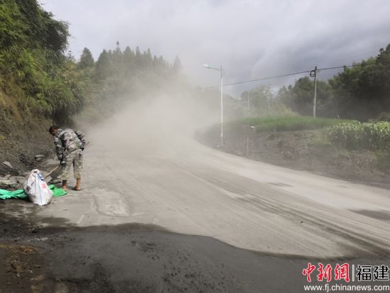 養(yǎng)路工帶上防塵口罩利用鐵鍬、竹掃把等工具清理灑落的水泥料。余思煥 攝